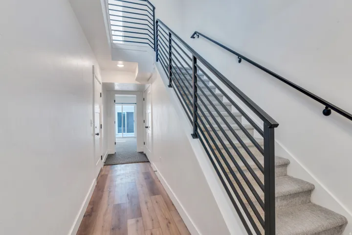 Modern staircase featuring horizontal metal railings and a black handrail