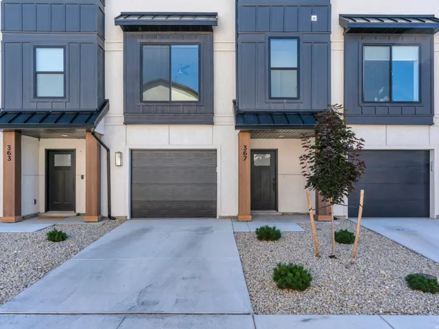 Modern townhome facade featuring a white stucco exterior with dark paneling accents