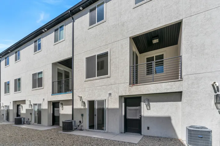 Contemporary stucco exterior featuring a recessed balcony with metal railings and a slat wood ceiling