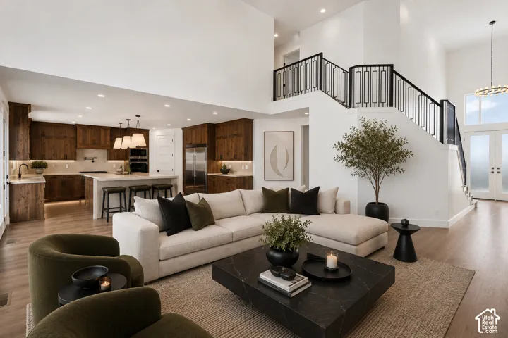 Vaulted great room with wood-finish flooring and a contemporary open-tread staircase featuring a geometric metal railing
