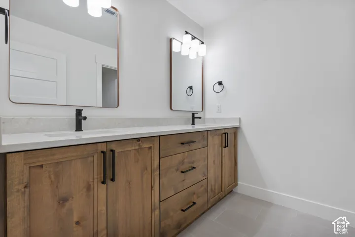 Double vanity featuring wood-finish cabinetry, integrated sinks, white countertops, and matte black fixtures