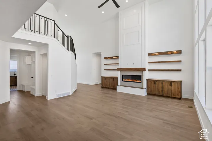 Spacious living area featuring a tall fireplace with a wood mantel, built-in cabinetry, and floating shelves