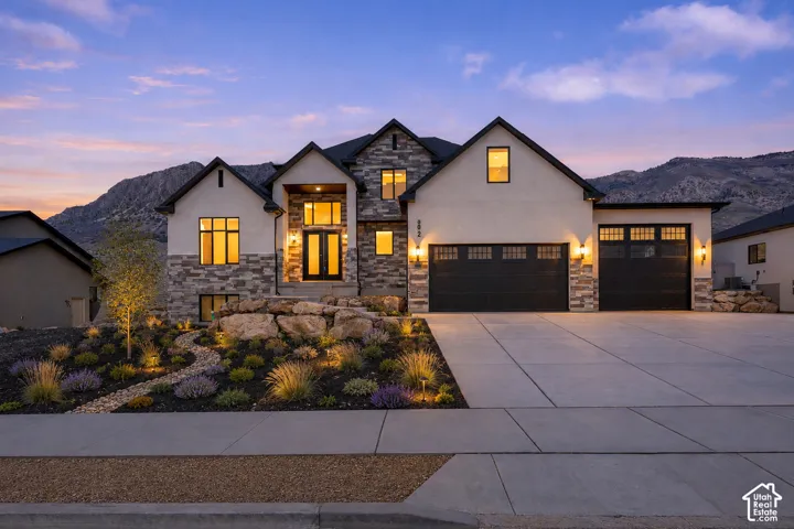 Modern architectural home featuring a striking stucco and stone exterior with multiple gabled rooflines and architectural peaks