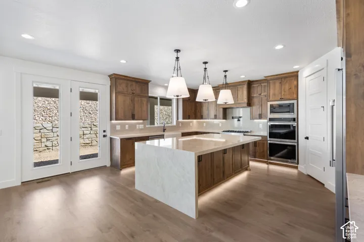 Spacious kitchen featuring wood-finish flooring, recessed lighting, and a large central island with integrated under-lighting