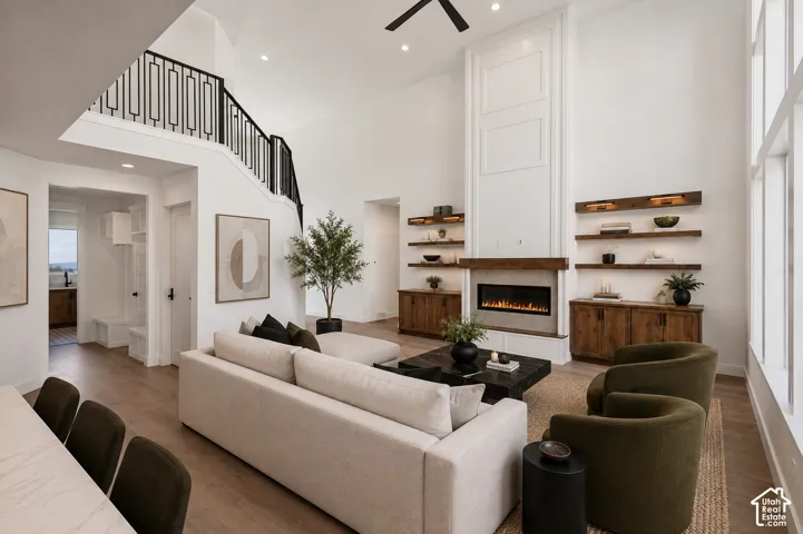 Great room featuring a two-story fireplace with a substantial mantel, built-in shelving, and wood-finish flooring