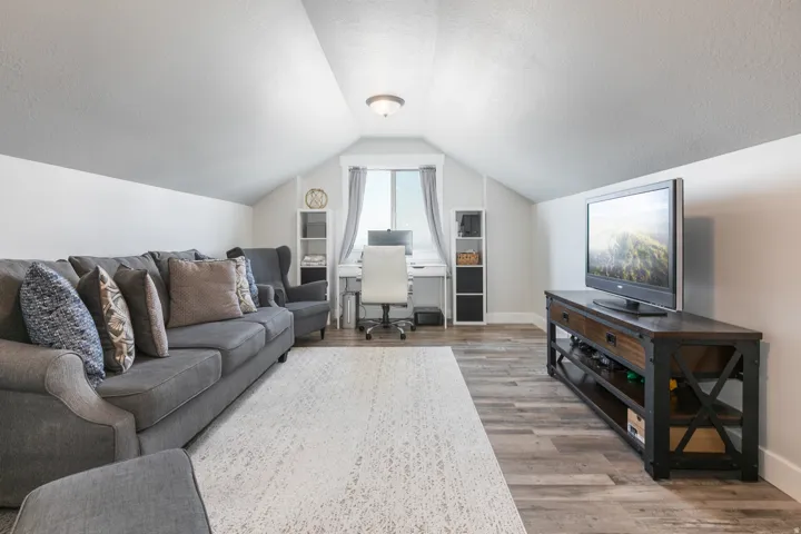 Attic room with angled ceilings, wood-finish flooring, recessed window, and built-in shelving