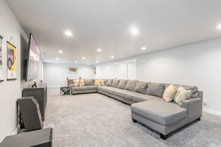 Spacious interior room featuring light gray walls, recessed ceiling lighting, and gray carpeting