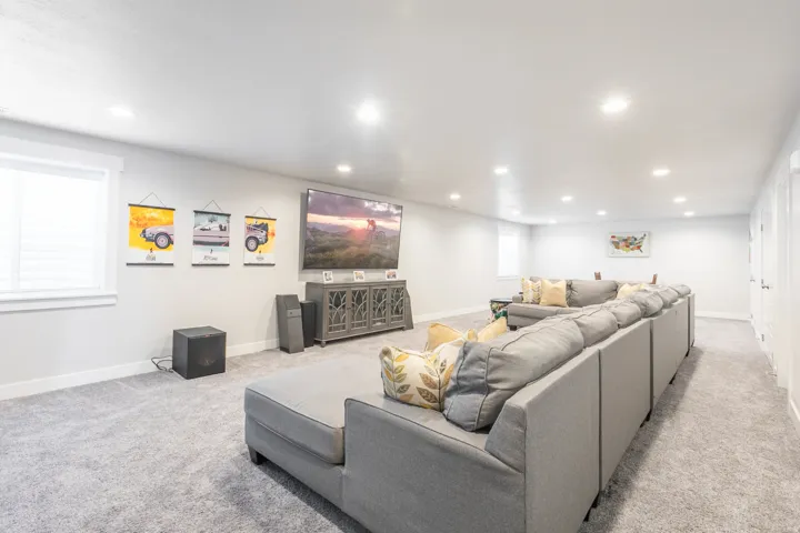 Spacious entertainment area with neutral gray carpeting and recessed lighting