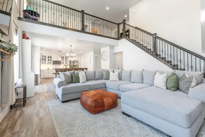 Two-story living area featuring a prominent staircase with black wrought iron spindles and dark wood railings