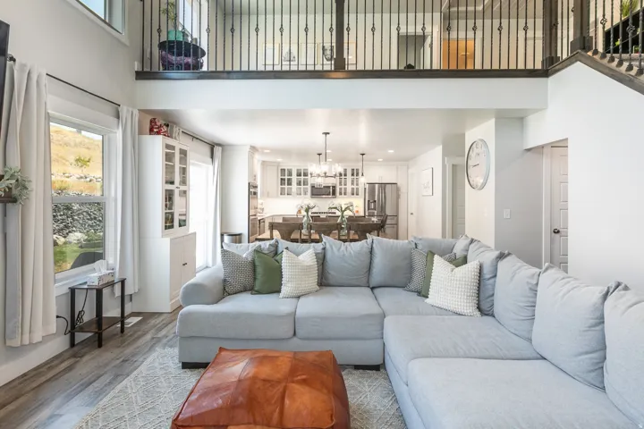 Spacious main living area featuring a two-story ceiling, open concept layout, wood-finish flooring, and a second-story balcony with metal balusters