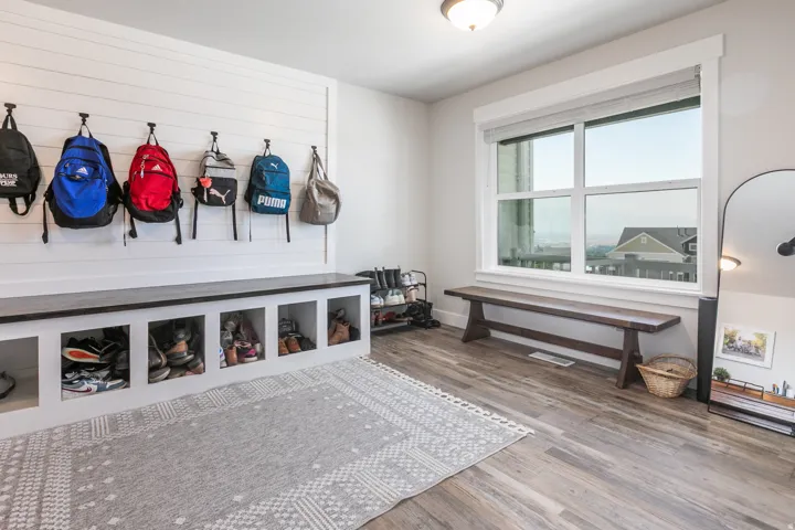 Entryway mudroom featuring a built-in bench with cubby storage, shiplap accent wall with wall hooks, and wood-finish flooring