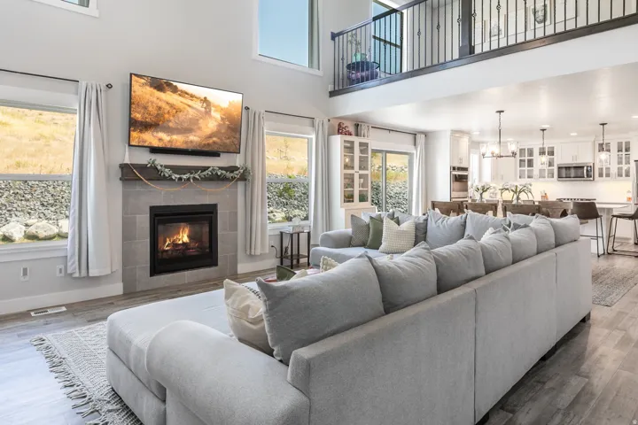Two-story living area with a floor-to-ceiling fireplace featuring a tiled surround and wood mantel