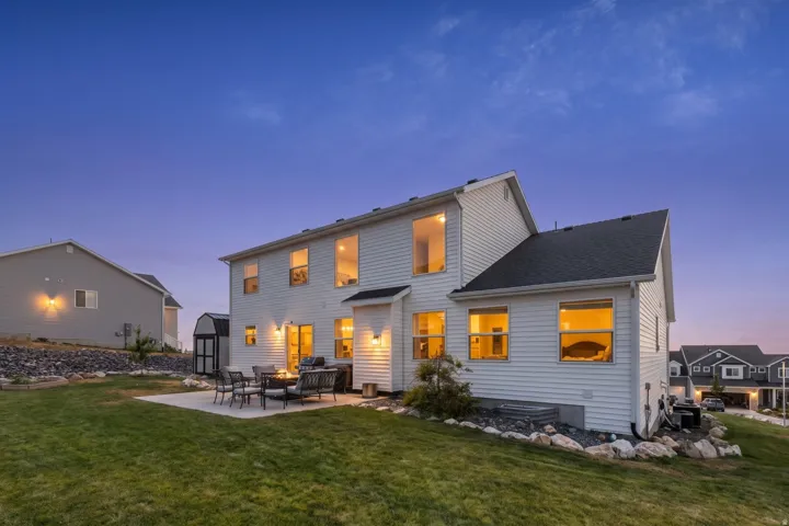 Expansive backyard featuring a concrete patio, manicured lawn, and decorative rock landscaping