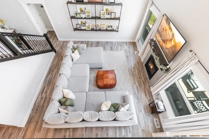 Open-concept living space featuring wood-finish flooring, a wall-mounted shelving unit, and a fireplace with a mantel