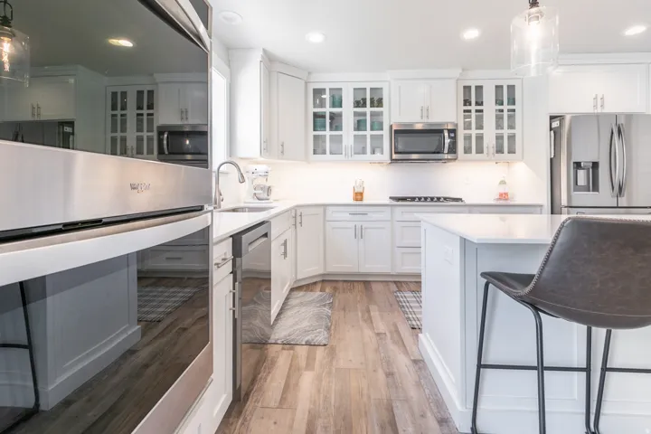 Kitchen featuring white cabinetry, wood-finish flooring, stainless steel appliances, a white subway tile backsplash, and recessed lighting