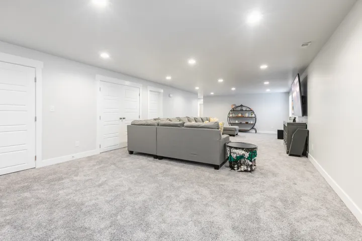 Expansive carpeted room featuring recessed lighting, a built-in entertainment area, and multiple panel doors with white trim