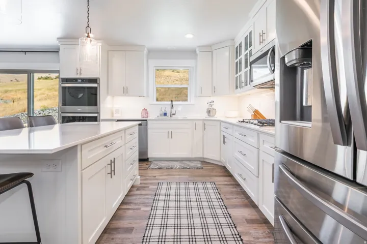 Contemporary kitchen featuring white cabinetry, stainless steel appliances, wood-finish flooring, a white countertop island, and recessed lighting