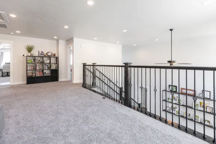 Spacious carpeted landing featuring black wrought iron balusters and dark wood newel posts
