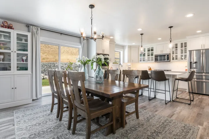 Open-concept dining area featuring wood-finish flooring, a contemporary chandelier, and a built-in display cabinet