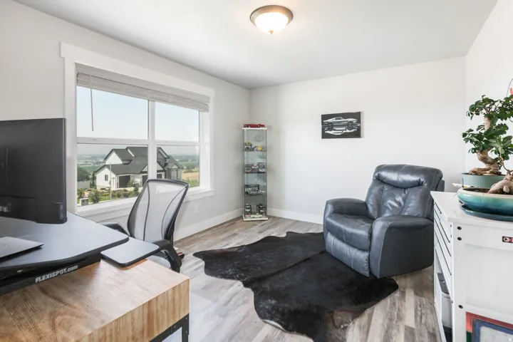 Bright room featuring a large window with white trim, wood-finish flooring, and light-toned walls