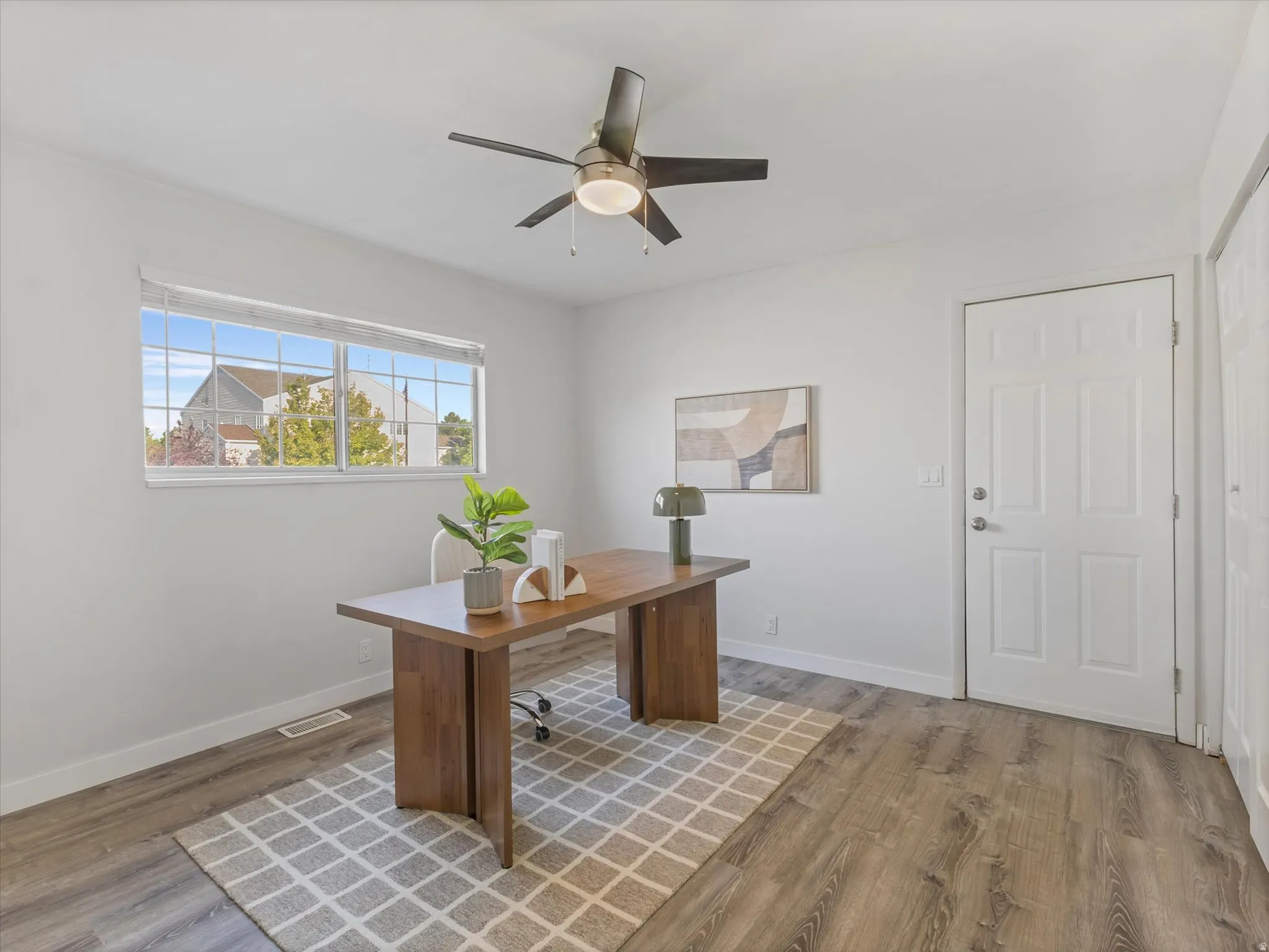 Room featuring wood-finish flooring, a ceiling fan with integrated lighting, and a window with blinds