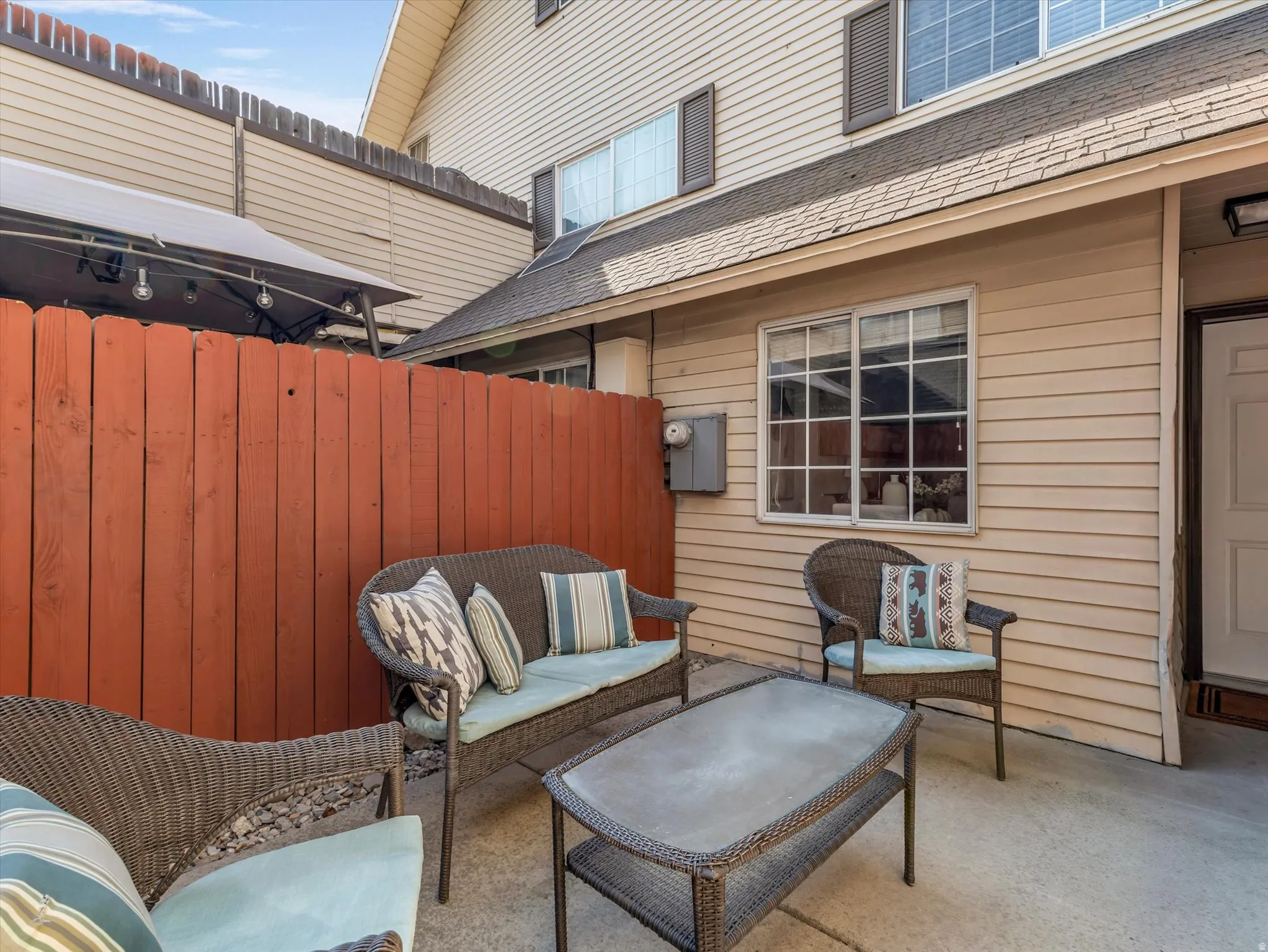 Private concrete patio featuring a reddish-brown privacy fence