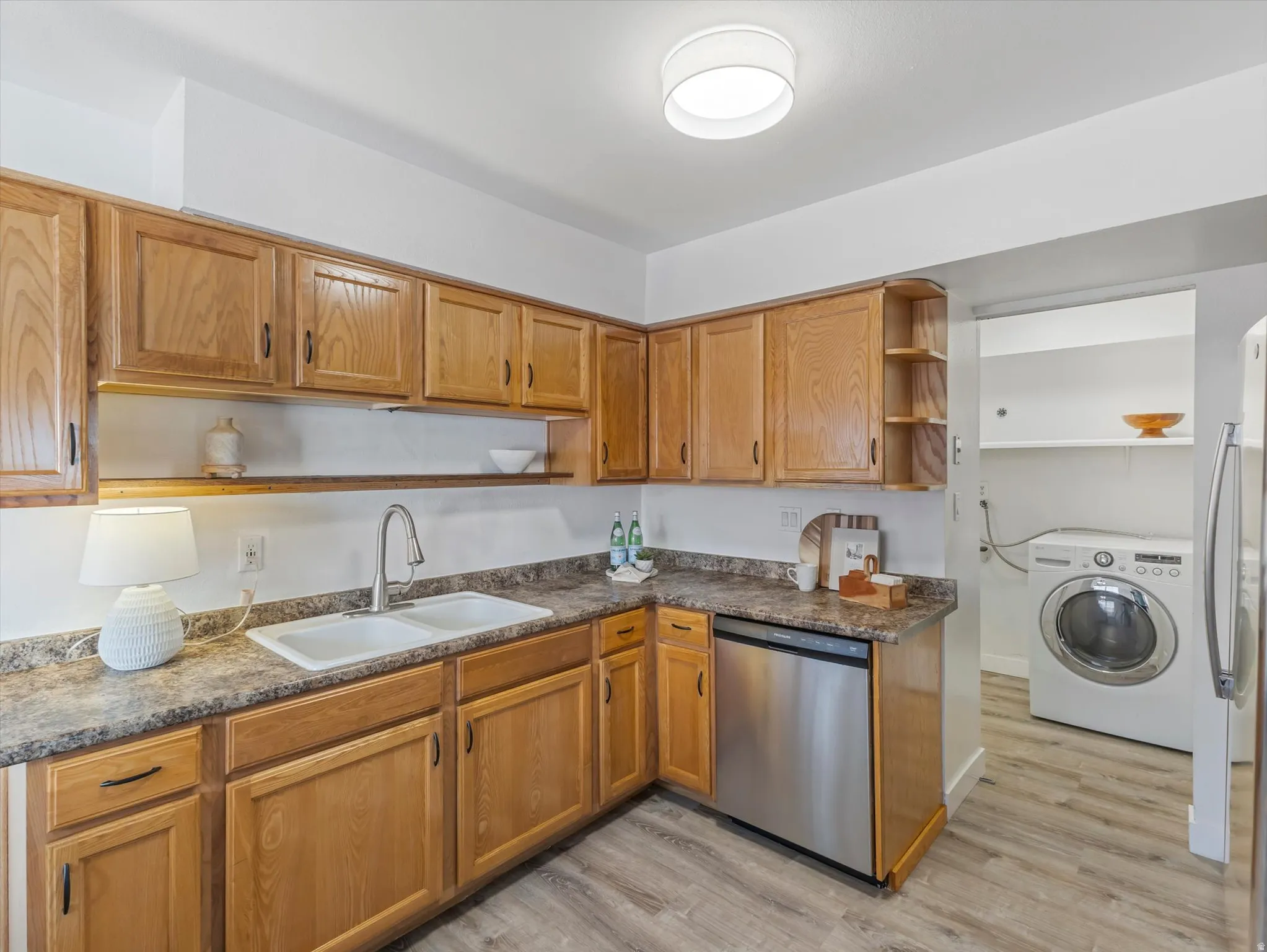 Kitchen area with wood-finish cabinetry, a double basin sink, and a stainless steel dishwasher