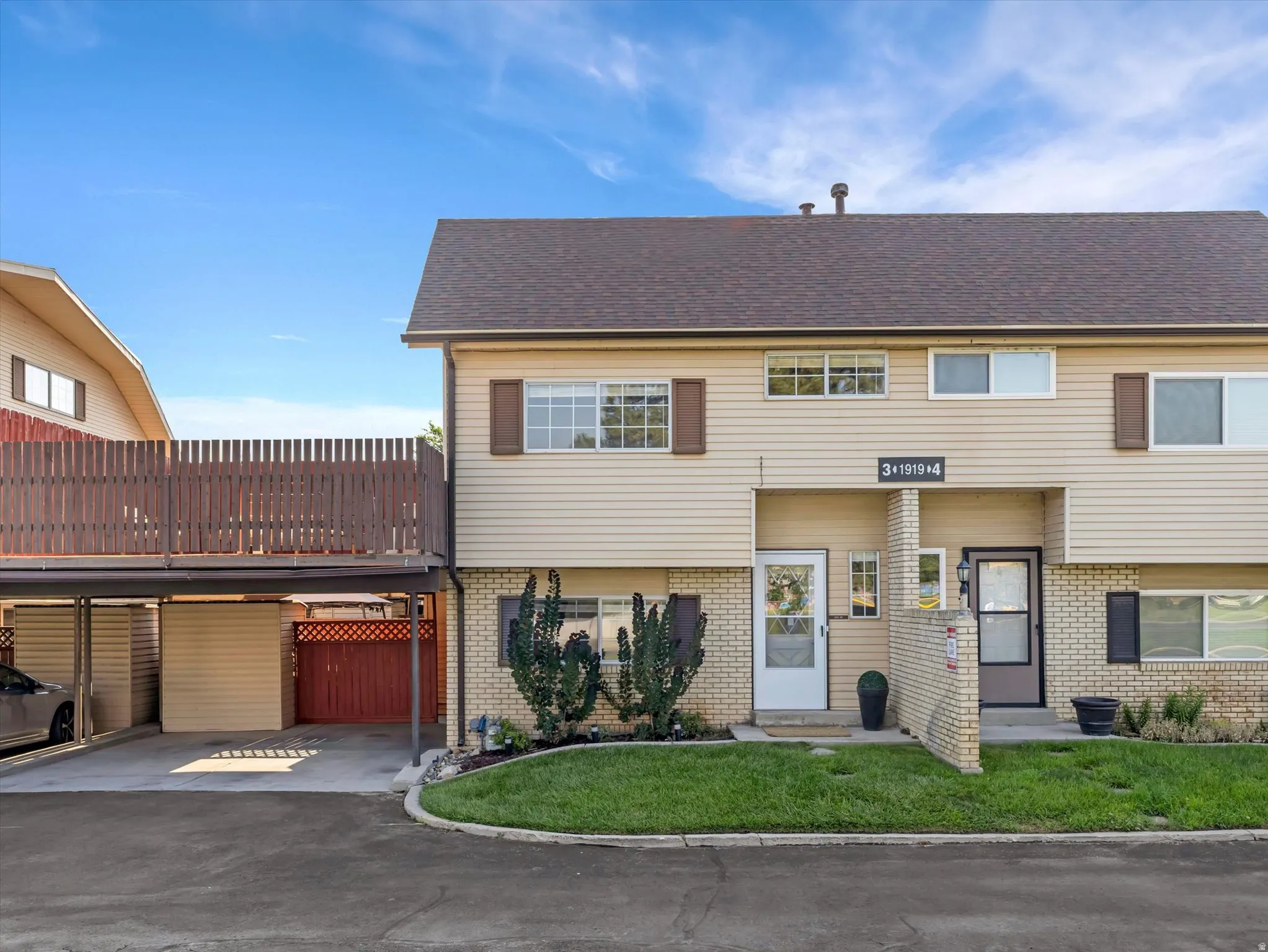 Two-story townhome with tan siding and a dark brown shingle roof