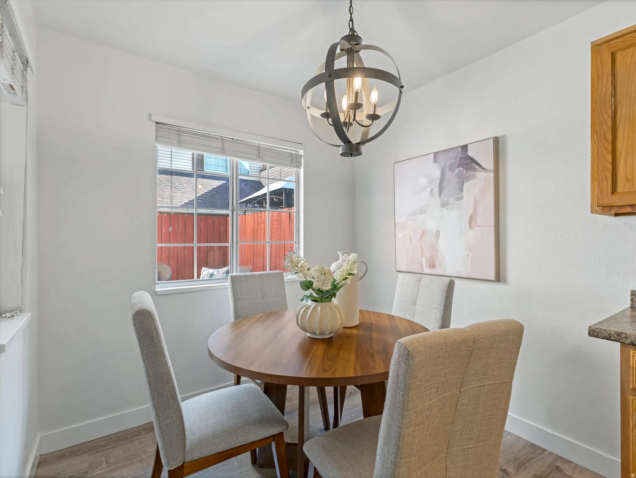 Dining space featuring a spherical chandelier with exposed bulbs, a single window with horizontal blinds, and wood-finish flooring