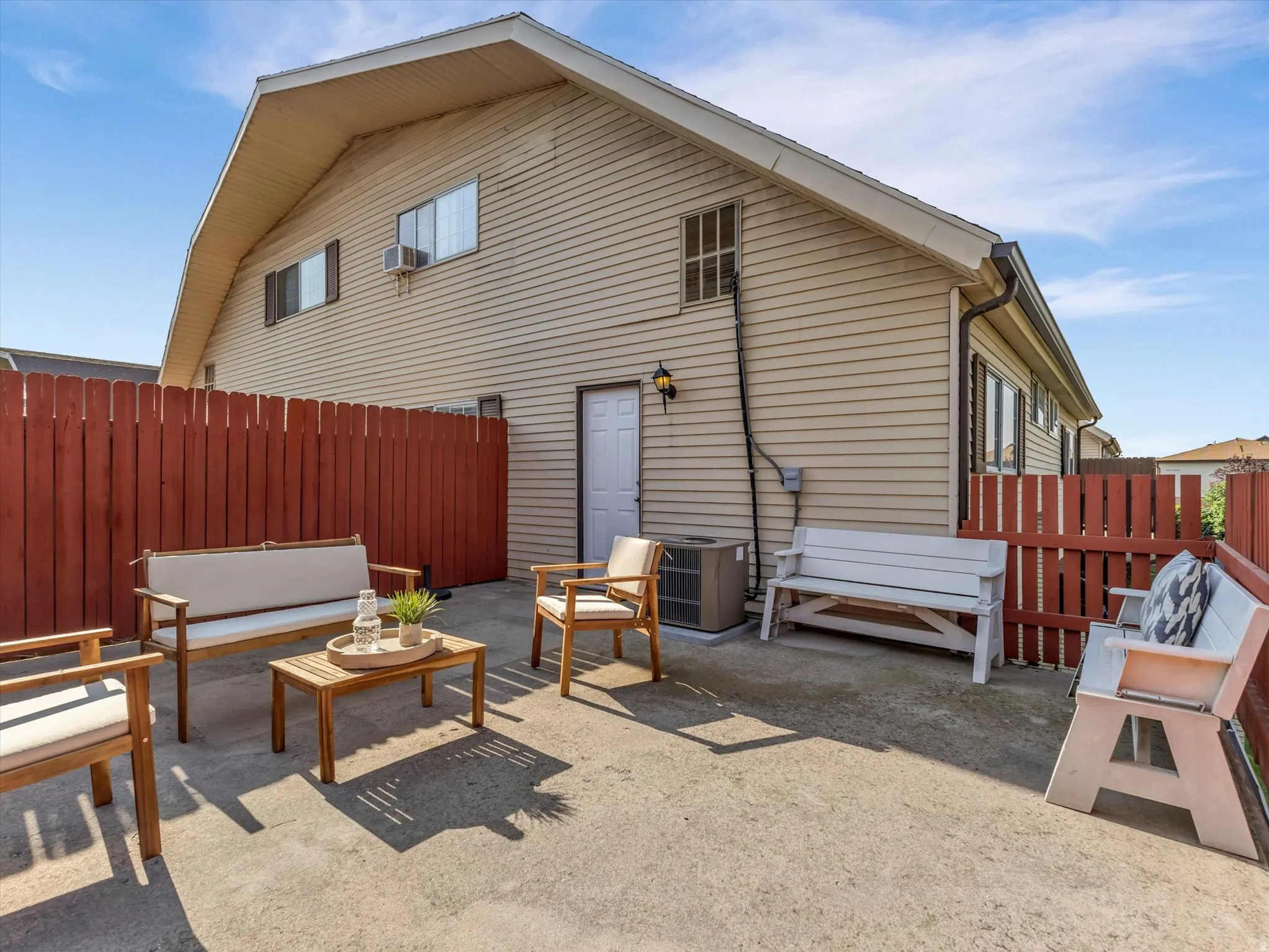 Private concrete patio area enclosed by a red wooden fence