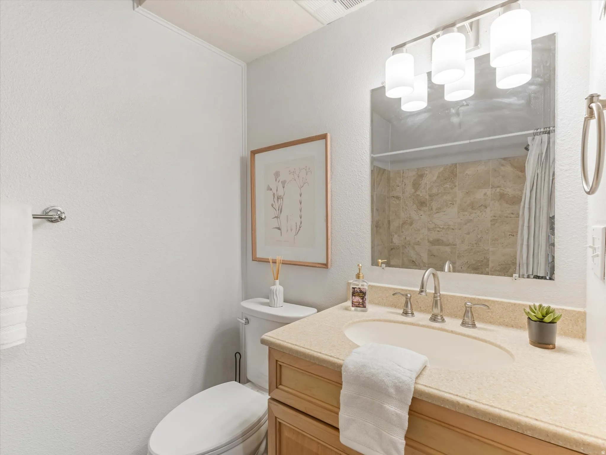 Bathroom featuring a vanity with an integrated sink, a light-toned countertop, and a brushed nickel faucet