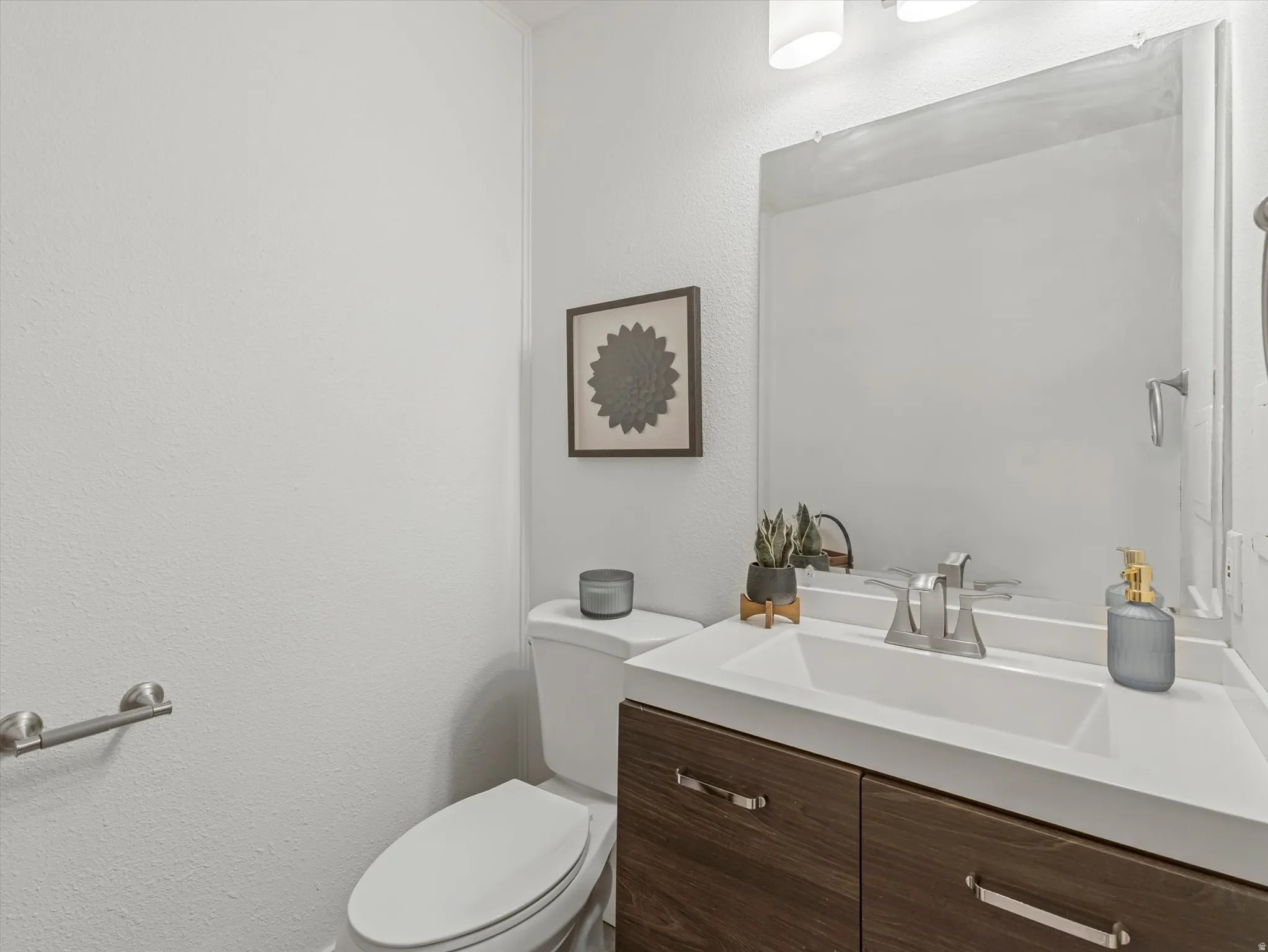 Modern vanity with a recessed basin sink, chrome faucet, and wood-finish cabinetry featuring brushed nickel pulls