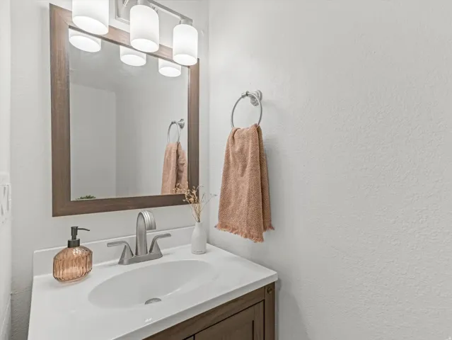 Bathroom vanity featuring a white countertop, undermount sink, and brushed nickel faucet