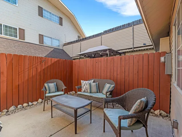 Private patio space featuring a concrete slab, red-stained vertical plank fencing, and decorative stone landscaping