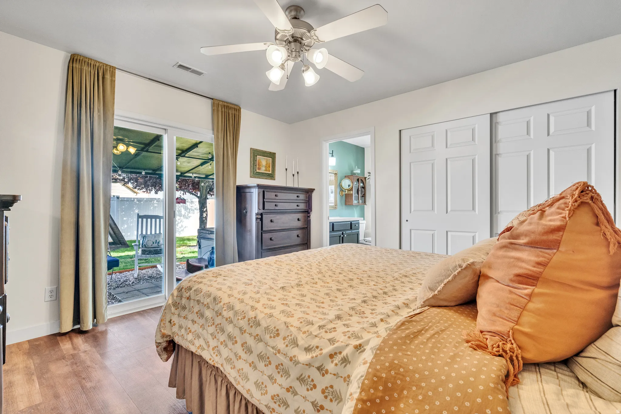 Room featuring wood-finish flooring, a ceiling fan with integrated lighting, and white sliding closet doors