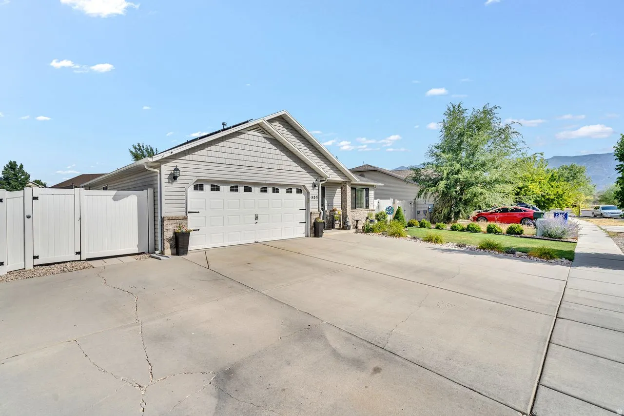 Front exterior featuring an attached two-car garage, concrete driveway, and side yard access through a white privacy gate