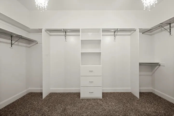 Walk-in closet featuring built-in shelving, hanging rods, and integrated drawers