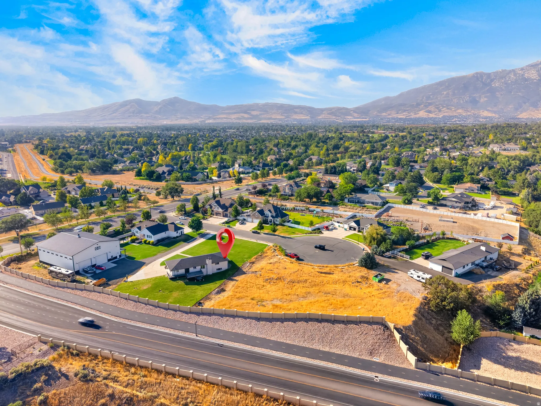 Expansive property featuring a single-story residence with a green lawn, established landscaping, and a paved driveway