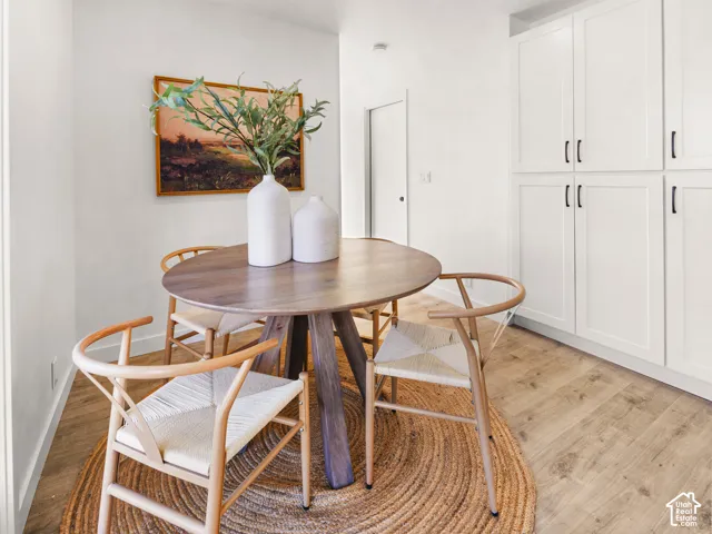 Wood-finish flooring, white flat-panel cabinetry, and a solid wood dining table