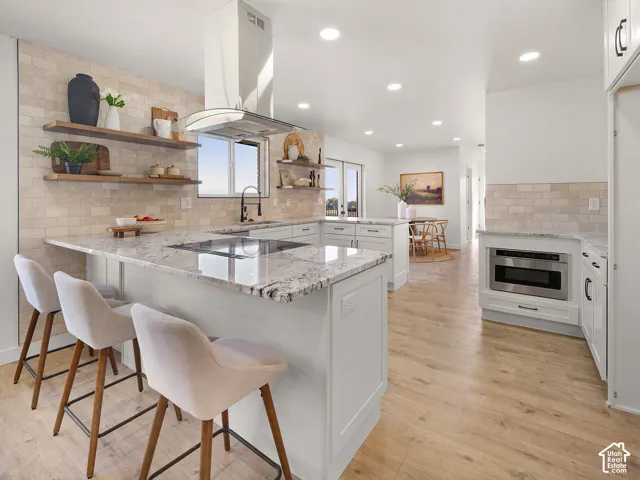Kitchen featuring granite countertops, a built-in cooktop, light wood-finish flooring, white cabinetry, and recessed lighting