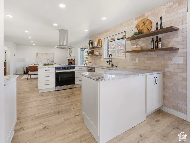 White shaker cabinetry with granite countertops, wood-finish flooring, a stainless steel range with a ventilation hood, and a subway tile backsplash