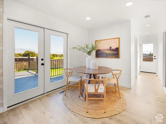 Double French doors opening to an exterior deck, recessed ceiling lighting, light wood-finish flooring, and white painted walls