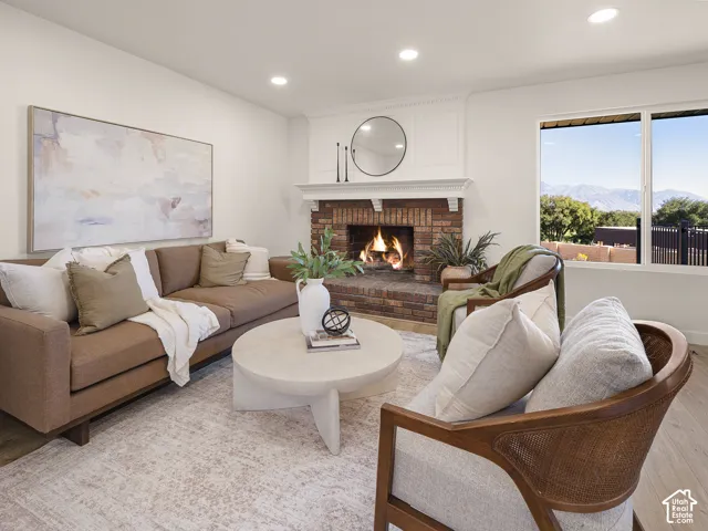 Brick-clad fireplace with a white mantel, recessed lighting, and wood-finish flooring