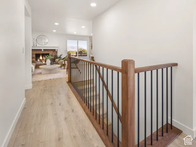 Hardwood staircase with black metal balusters, recessed lighting, and wood-finish flooring