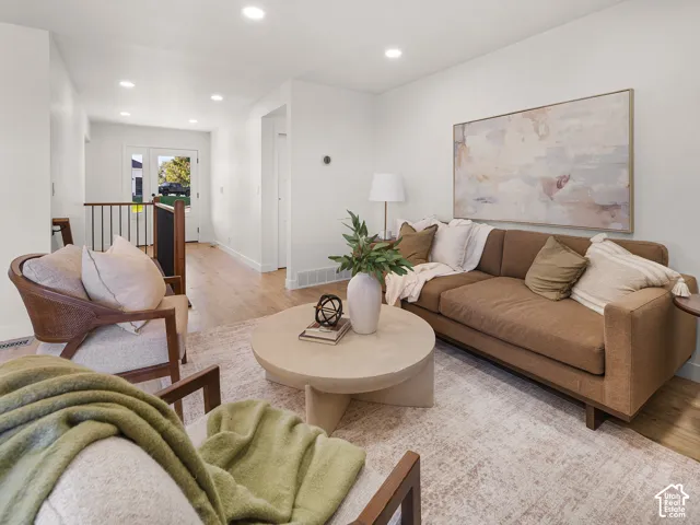 Recessed lighting illuminates the living space with wood-finish flooring
