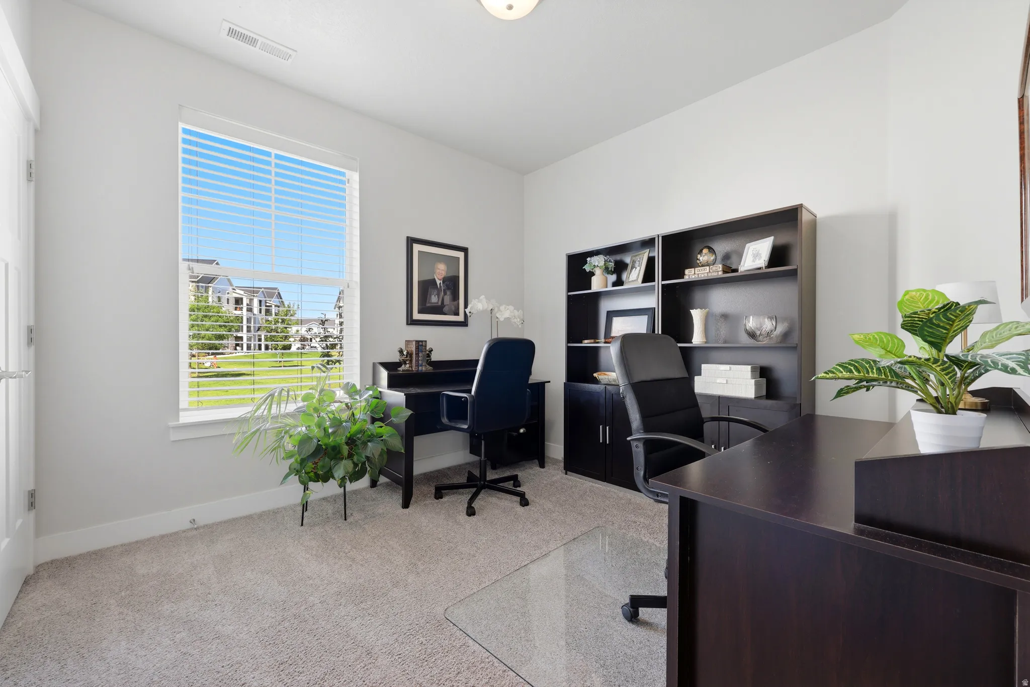 Carpeted room with a large window featuring horizontal blinds
