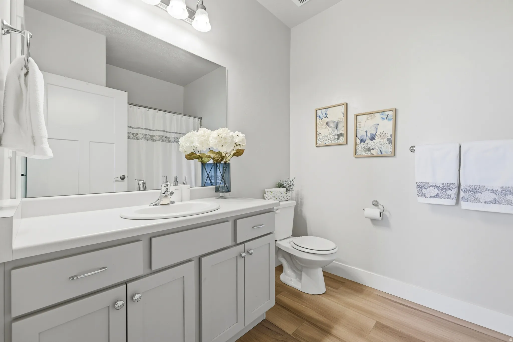 Spa-inspired bathroom featuring a gray vanity with dual sinks, white quartz countertop, and polished chrome fixtures