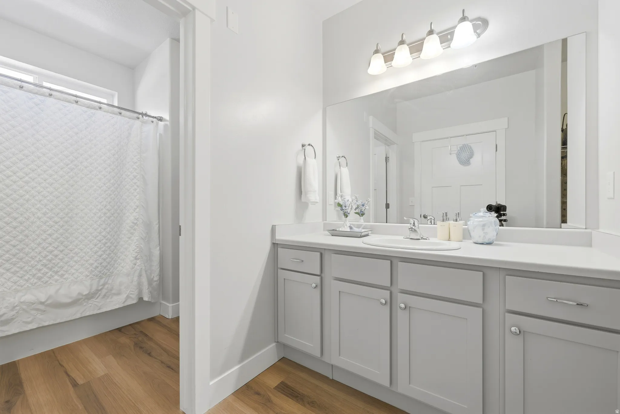 Spa-inspired primary bathroom showcasing a generous double-vanity with gray cabinetry, white quartz countertop, and chrome faucet fixtures