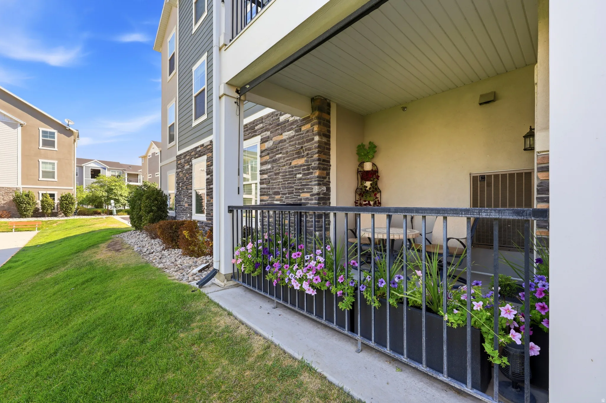 Ground-level patio with a covered ceiling, bordered by a black metal railing