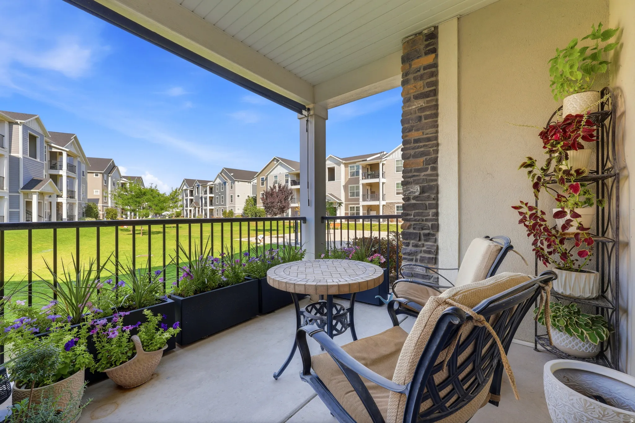 Covered balcony featuring a stone veneer column, solid railing, and built-in planters